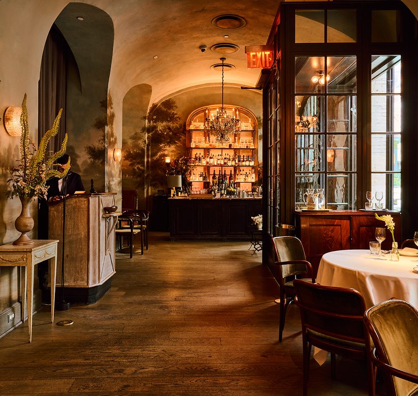 Elegant interior of Le Cou Cou restaurant with warm lighting, arched doorways, and intimate dining tables