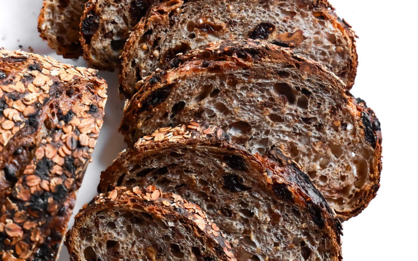 Thick slices of artisan cranberry walnut sourdough bread with an open crumb and oat-crusted crust